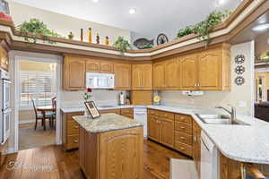 Kitchen featuring white appliances, dark hardwood / wood-style floors, kitchen peninsula, and sink