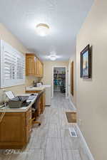 office with washer / clothes dryer, built in desk, and a textured ceiling