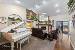 Living room featuring a tiled fireplace, vaulted ceiling, and hardwood / wood-style floors