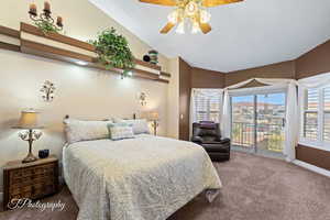 Carpeted bedroom featuring ceiling fan, vaulted ceiling, and access to outside