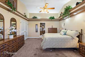 Carpeted bedroom with ensuite bath, high vaulted ceiling, a closet, and ceiling fan