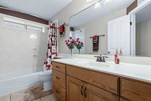 Full bathroom featuring toilet, tile patterned floors, shower / bathtub combination with curtain, and vanity