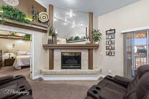 Living room with carpet floors, a tile fireplace, and a textured ceiling