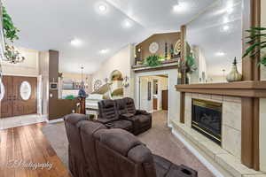 Living room with a tile fireplace, lofted ceiling, a textured ceiling, and a chandelier