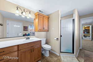 Bathroom featuring vanity, toilet, and a shower with shower door