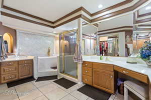 Bathroom with tile patterned flooring, vanity, ornamental molding, and separate shower and tub