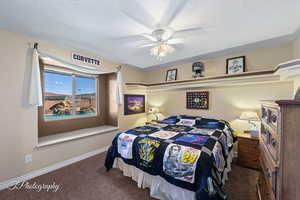 Carpeted bedroom featuring a textured ceiling and ceiling fan