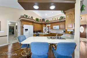 Kitchen featuring vaulted ceiling, sink, a kitchen bar, kitchen peninsula, and white appliances