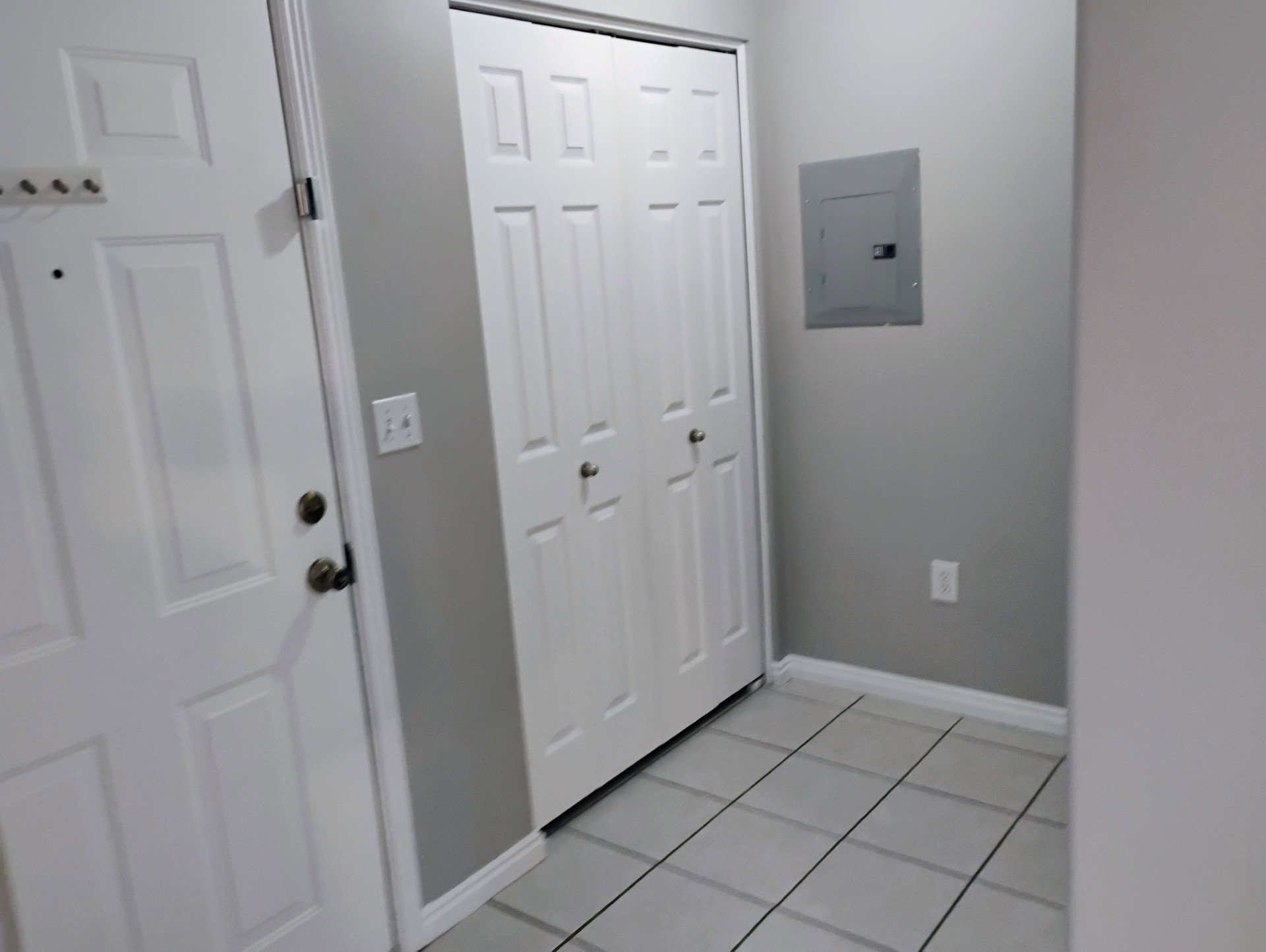 Foyer entrance with baseboards, electric panel, and light tile patterned floors