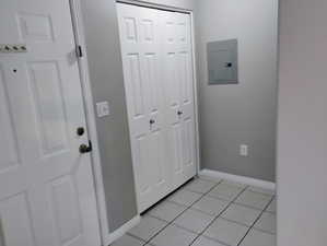 Foyer entrance with baseboards, electric panel, and light tile patterned floors