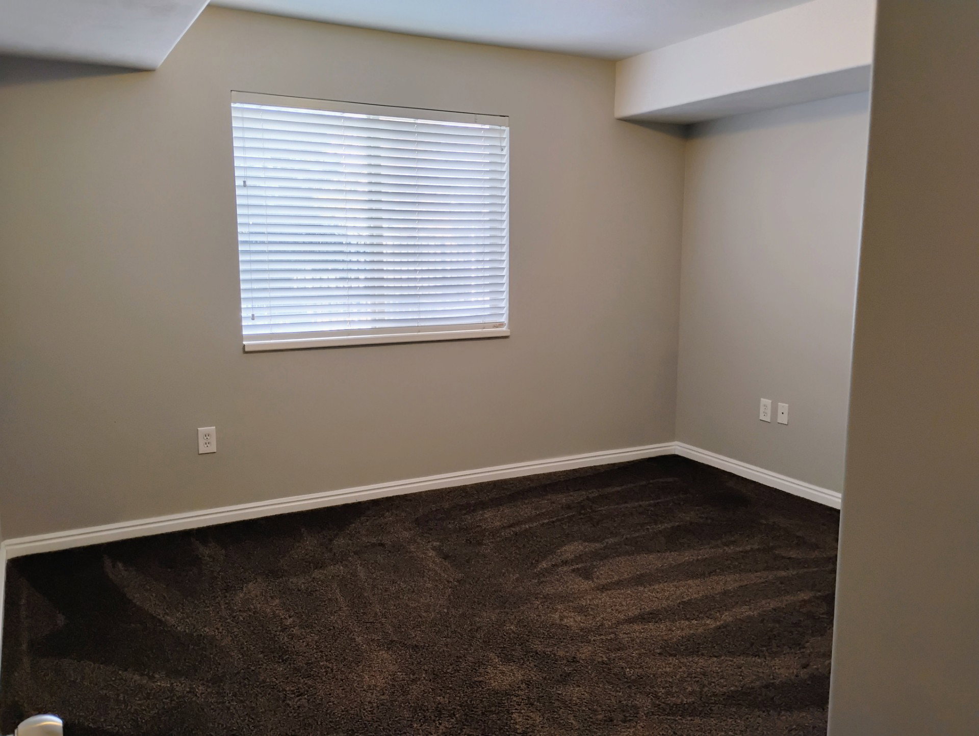 Empty room featuring baseboards and dark carpet