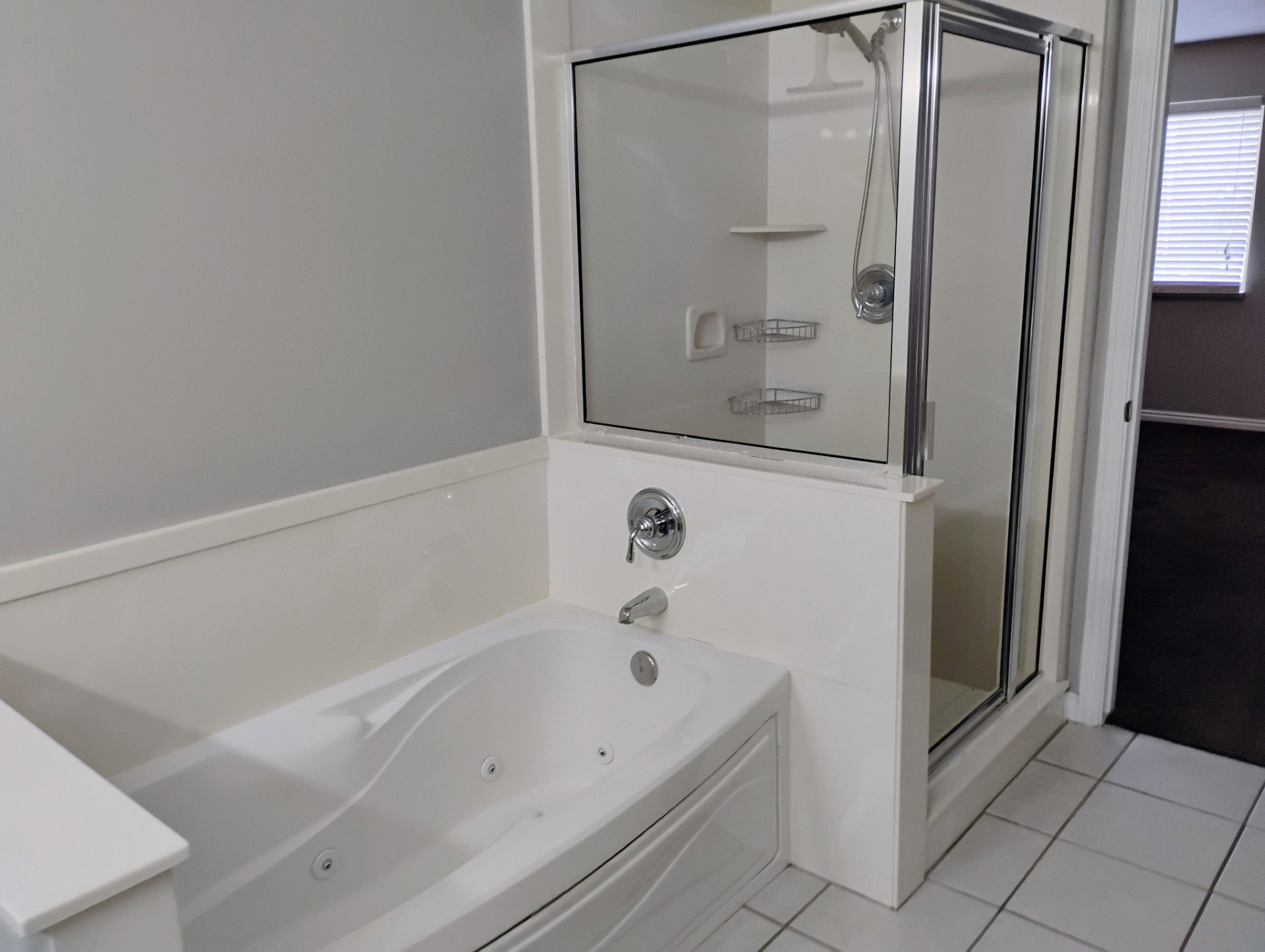 Bathroom with a tub with jets, tile patterned floors, and a shower stall