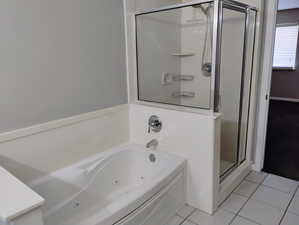 Bathroom with a tub with jets, tile patterned floors, and a shower stall