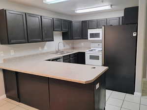 Kitchen with light countertops, a peninsula, a sink, and stainless steel appliances