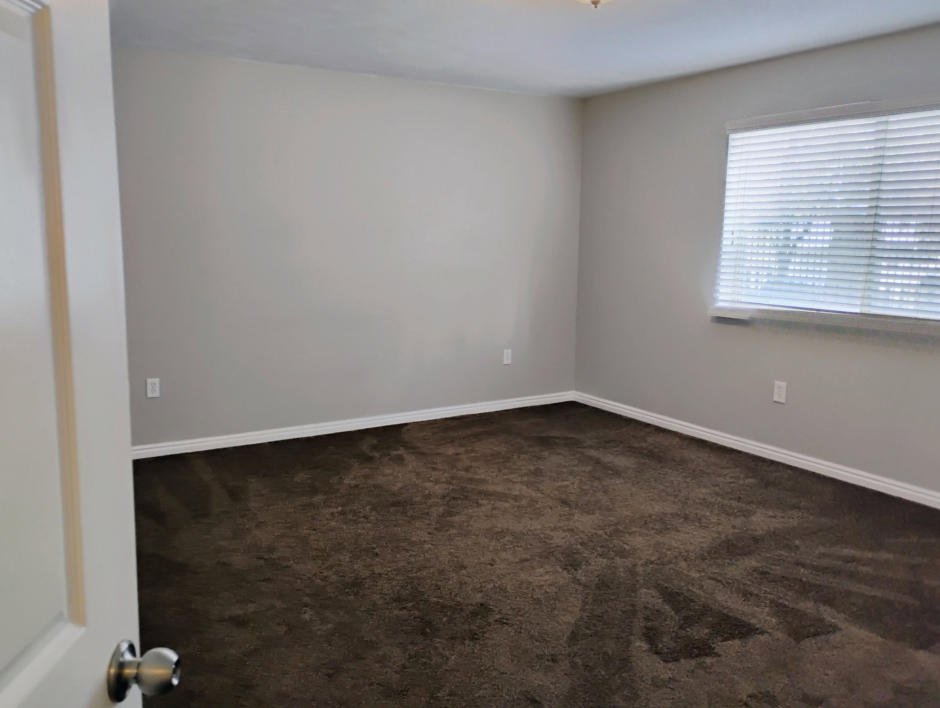 Empty room with baseboards and dark carpet