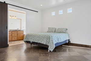 Bedroom with ensuite bathroom, a barn door, and sink