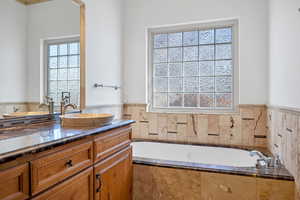 Bathroom featuring vanity and tiled bath