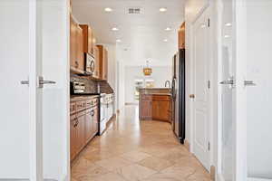 Kitchen with stainless steel appliances, pendant lighting, light stone counters, and decorative backsplash