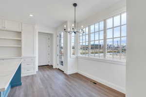 Unfurnished dining area with light wood-style floors, visible vents, baseboards, and a notable chandelier