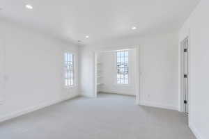 Empty room featuring plenty of natural light, light colored carpet, and recessed lighting