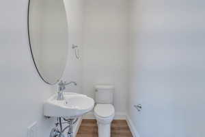 Bathroom with toilet, wood finished floors, and baseboards