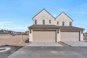 View of front of property featuring stucco siding, driveway, and a garage