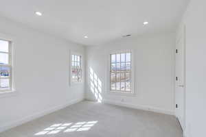 Empty room with recessed lighting, visible vents, light carpet, and baseboards