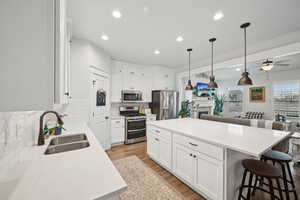 Kitchen featuring sink, white cabinets, backsplash, a center island, and stainless steel appliances