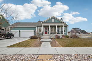 View of front of home with a porch, a garage, and a front lawn