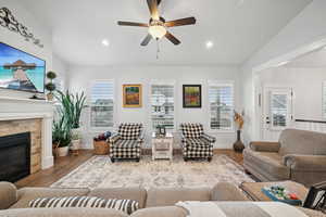 Living room with lofted ceiling, wood-type flooring, a tile fireplace, and a healthy amount of sunlight