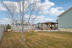 View of yard featuring a trampoline, a gazebo, a patio area, and a playground