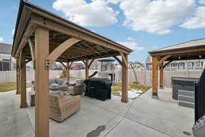 View of patio featuring a playground, area for grilling, an outdoor hangout area, a hot tub, and a gazebo