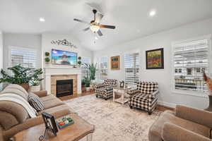 Living room with hardwood / wood-style flooring, ceiling fan, vaulted ceiling, and a tile fireplace