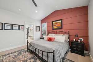 Bedroom with ensuite bathroom, vaulted ceiling, carpet floors, and ceiling fan