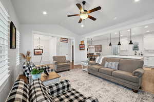 Living room with lofted ceiling, sink, ceiling fan with notable chandelier, and light hardwood / wood-style flooring