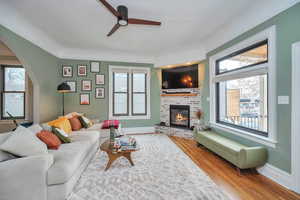 Living room featuring hardwood / wood-style floors, a brick fireplace, and ceiling fan