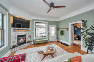 Living room featuring hardwood / wood-style flooring, a brick fireplace, a healthy amount of sunlight, and ceiling fan