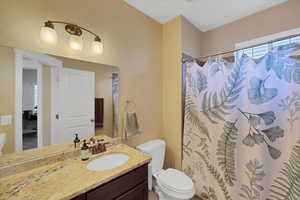 Bathroom featuring walk in shower, vanity, and toilet