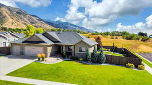 View of front of house with a garage, a mountain view, and a front lawn