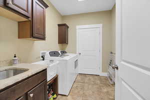 Laundry room with cabinets, washer and clothes dryer, and light tile patterned floors