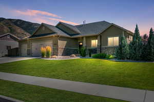 View of front of home with a mountain view, a garage, and a lawn