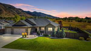 View of front of home featuring a garage, a mountain view, and a lawn