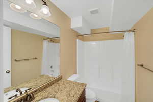 Full bathroom with vanity, shower / tub combo, and toilet