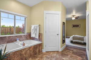 Bathroom with ceiling fan and tiled tub