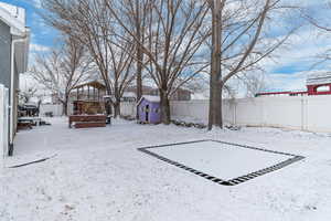 Snowy yard featuring a storage unit