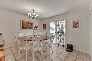 Tiled dining room featuring a notable chandelier and a textured ceiling