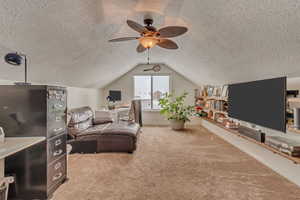 Carpeted bedroom featuring lofted ceiling, a textured ceiling, and ceiling fan