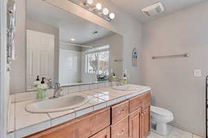 Bathroom featuring vanity, walk in shower, tile patterned floors, and toilet