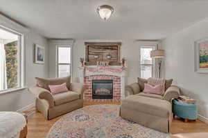 Living room featuring a brick fireplace, plenty of natural light, and light wood-type flooring