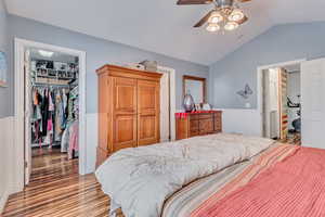 Bedroom with lofted ceiling, ceiling fan, dark hardwood / wood-style flooring, a walk in closet, and a closet